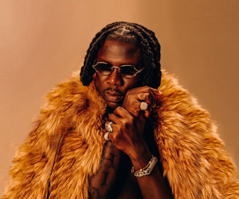 Stonebwoy in dark spectacles with a silky fur around his neck.
