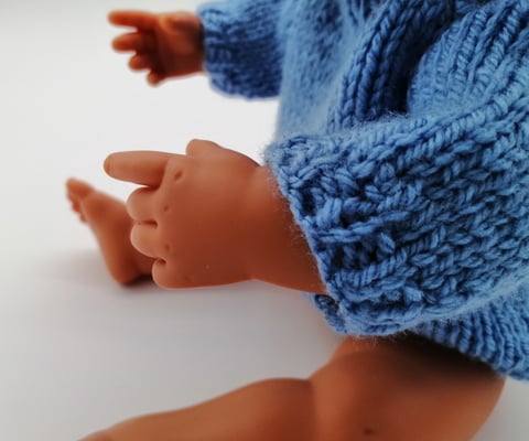 Miniland doll sitting wearing blue knitted jumper