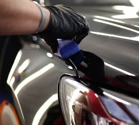 Especialista limpiando los faros delanteros del coche para restaurar su claridad y brillo.