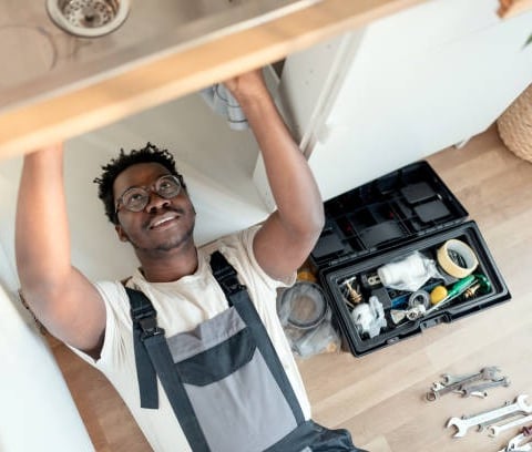 black man working under a sink