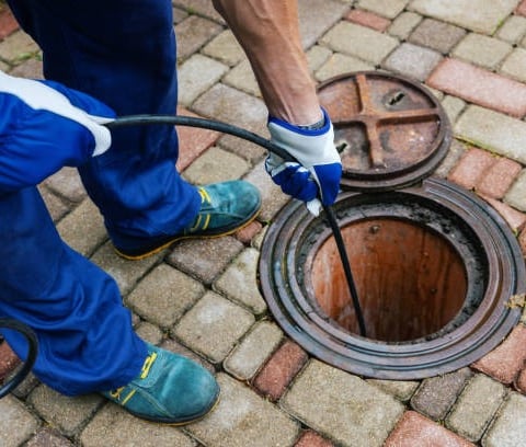 plumber cleaning a sewer line with a hose pump