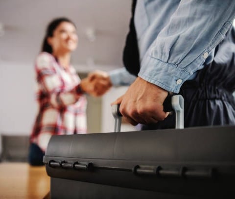 plumber making a deal with a prospect while holding a black tool box