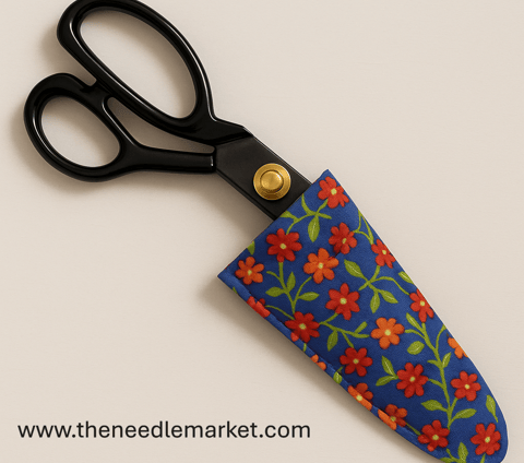 A pair of black tailor’s shears with gold pivot detail partially enclosed in a handmade fabric case.