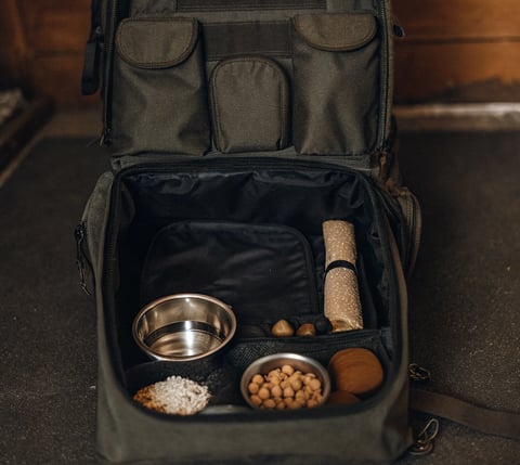 A pet travel kit packed with food, water bowls, and a toy.