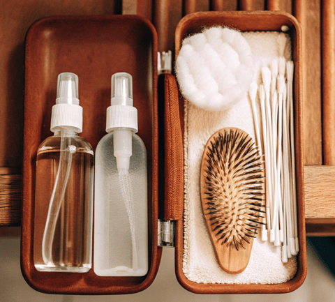 Pet-safe saline solution, cotton pads, and ear cleaning solution placed beside a cat grooming brush.