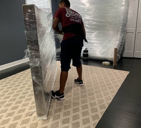 a man is protecting  a mattress with shrinkwrap. like a professional mover