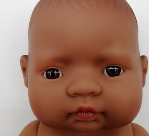 a Miniland baby doll with brown eyes
