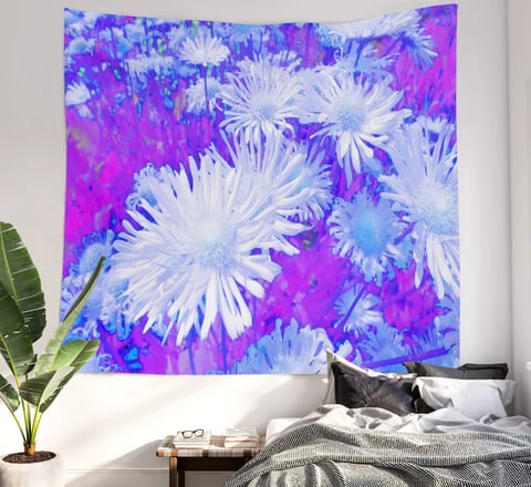 Wall tapestry on wall with a daisy flower printed design on it, bed underneath. 