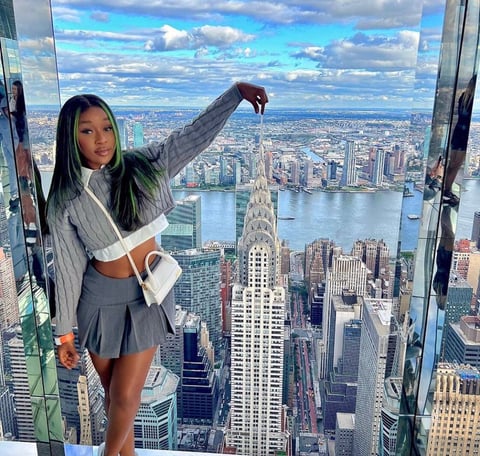 Efia Odo in a gray striped shirt and gray skirt posed behind New York City.