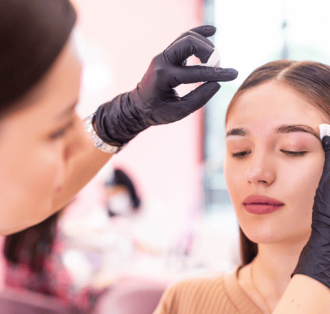 a woman getting her eyebrows done by a professional brow artist