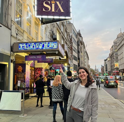 a woman standing on a sidewalk next to a london theatre