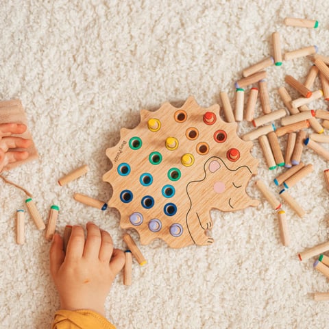 a child's hands playing with wooden pegons