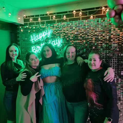 Mae and friends in front of the rose gold shimmer wall and happy birthday neon, Redlands.