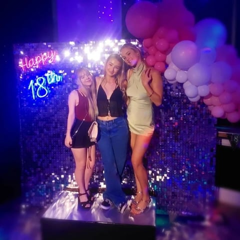 Maddie and her friends in front of the silver shimmer wall and happy 18th neon, Brisbane