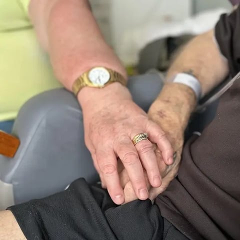 Carly's mum holding dads hand in hospital in his last couple of weeks.