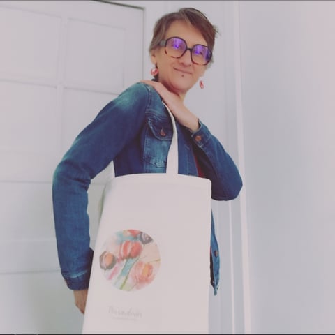 a woman in glasses and a denim jacket is holding a bag