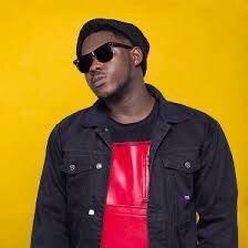 Medikal in a black jeans shirt wearing dark sunglasses.