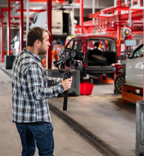 a man in a plaid shirt is holding a video camera