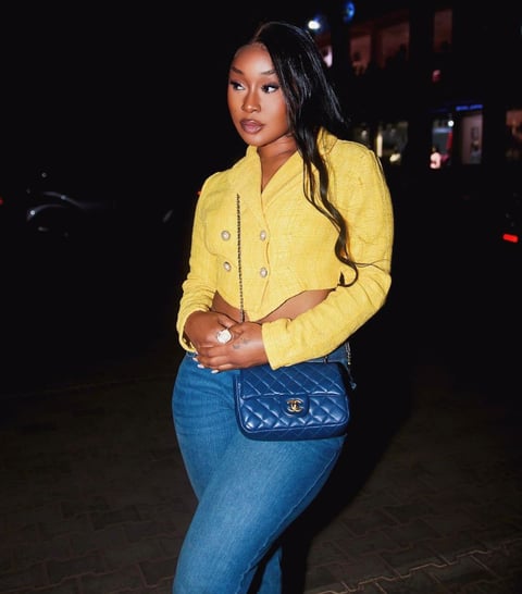 Efia Odo in a yellow top and a black jeans trousers strapped with a Coco Chanel bag.