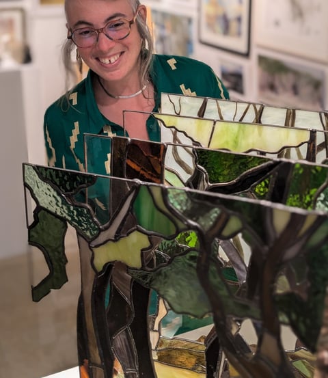 Image of Artist Laura Kriefman at Biennale Exhibition opening. Laura is smiling and looking at her bespoke glass art