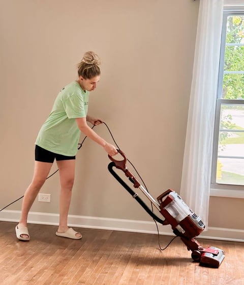 A professional cleaner pre-vacuums the hard floor