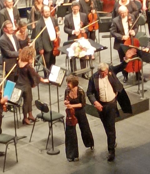 The conductor, accompanied by lead violinist .