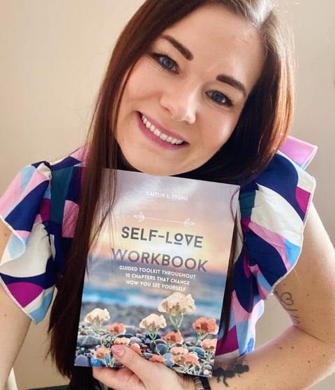 woman holding self love workbook