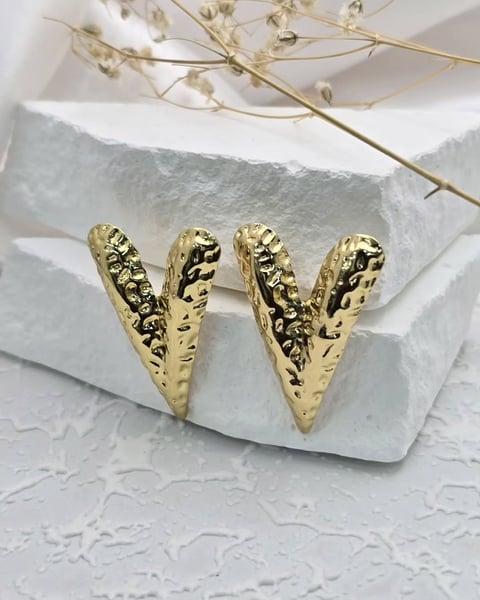 a pair of gold toned earrings with a gold leaf design