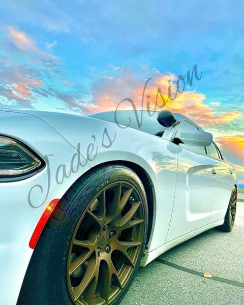 A white Dodge Charger with chrome hubcaps under a pink and blue cloudy sky on the Blue Ridge Parkway