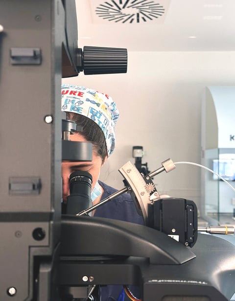 Fertility specialist conducting lab analysis under a microscope