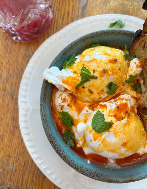 a bowl of eggs on toasted bread with a slice of bread