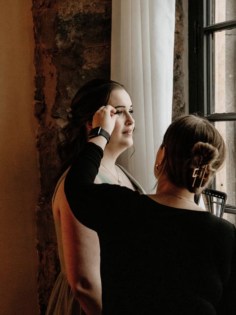 Makeup artist adjusting a bridesmaid’s false lashes.