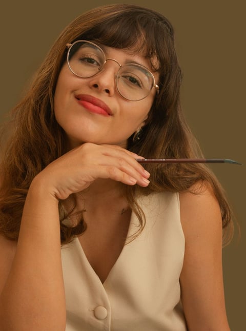 Foto de perfil da Leile segurando um pincel e sorrindo