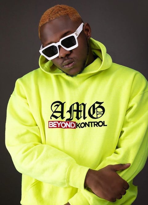 Medikal in a lemon customized AMG Beyond Kontrol sweater in black sunglasses.