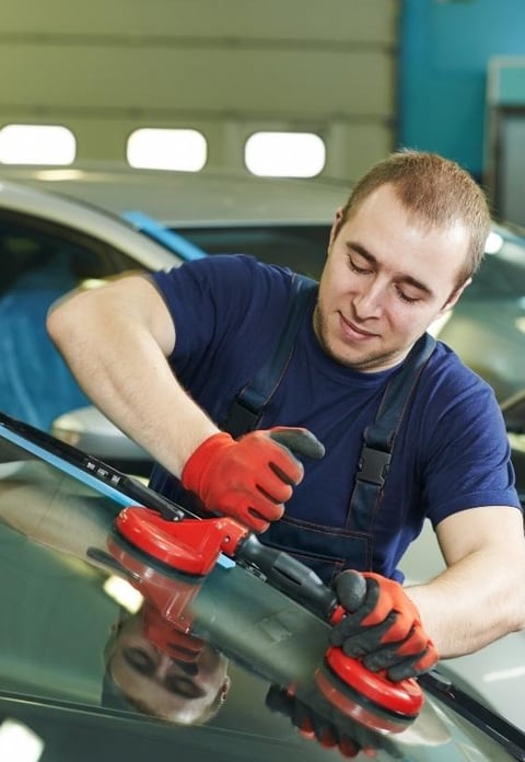 a man in a blue shirt is using a machine to polish a car