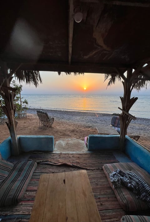 Terraço de um famoso salão de praia com sofá, mesa e cadeiras em frente à praia