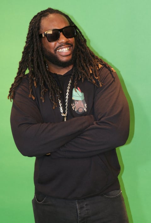 a man with dreadlocks and sunglasses on a green background