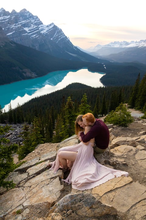 Couple sitting on a rock hugging at peyto lake