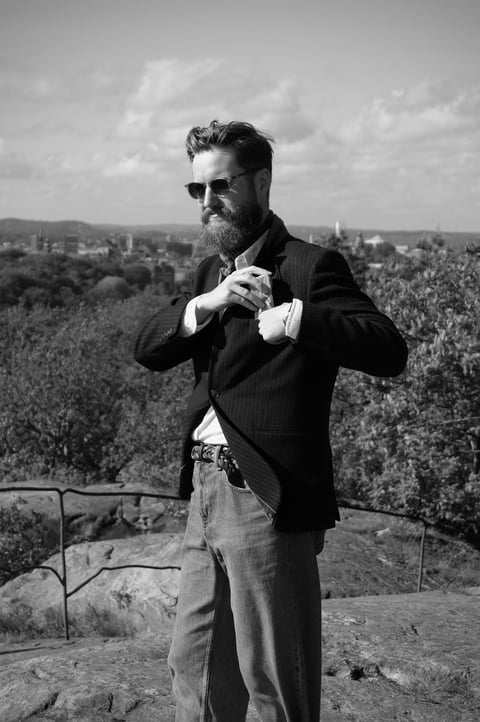 a man in a suit and sunglasses standing on a hilll