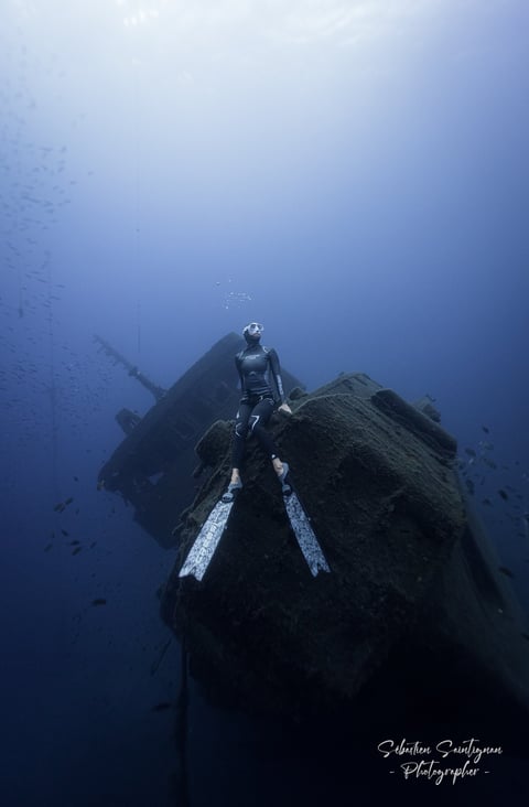 a freediver posing on top of a wreck ship. Photo taken by Sébastien Saintignan