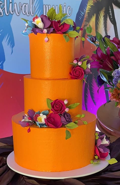 Bolo de três camadas decorado com flores em um evento, com um fundo colorido e vibrante representant