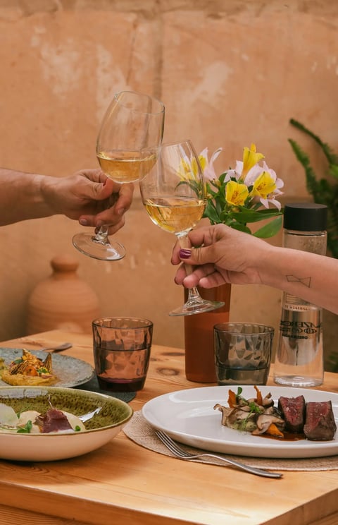 Dos copas brindan la comida que han pedido Es Mestral, se trata de solomillo, pescado fresco y unas alcachofas