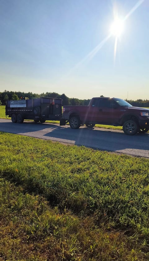 A truck pulling a dump trailer in nature.