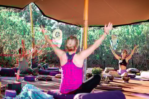 a woman in a pink tank top and black pants doing yoga