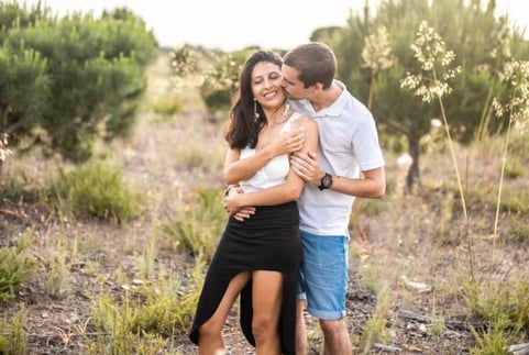 a couple standing in a field with their arms around each other
