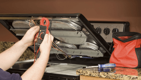 a man in a blue shirt is fixing a stove top