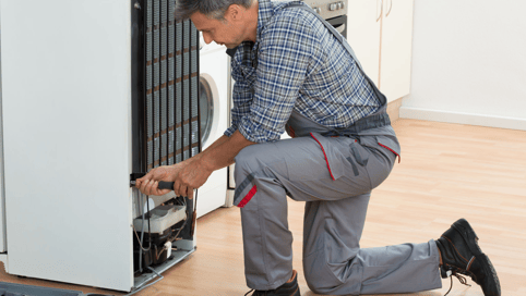 a man in a plaid shirt and pants is fixing a dishwasher