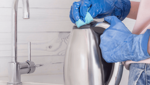 a person in a blue glove is cleaning a sink