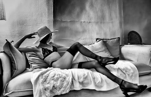 Photo artistique noire et blanc d'une élégante jeune femme en sous vêtements et bas  allongée sur un canapé 