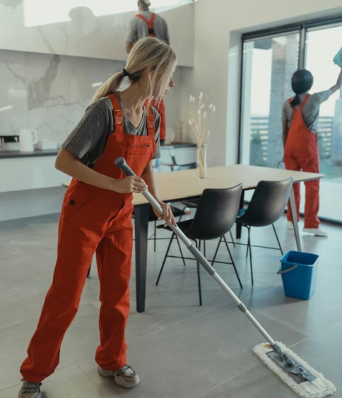 a woman in overalls and overalls cleaning a floor